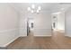 Well-lit dining area with wood-look floors, chair railing, contemporary chandelier, and adjoining access to the kitchen at 135 Weeping Willow Way, Tyrone, GA 30290