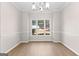 Dining room featuring chair rail, wood-look flooring, a modern chandelier, and a large window with outside views at 135 Weeping Willow Way, Tyrone, GA 30290