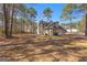 A view of the home's exterior showing an attached garage and an expansive lawn surrounded by trees at 135 Weeping Willow Way, Tyrone, GA 30290