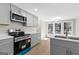 A modern kitchen with stainless steel appliances, gray cabinets and view into eating nook at 135 Weeping Willow Way, Tyrone, GA 30290