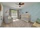 Bright Bedroom with crib, a glider chair, decorative wallpaper and natural light from the window at 1000 Maria Dr, Mcdonough, GA 30253