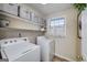 Well-lit laundry room with washer, dryer, shelving, and a window with patterned curtains at 1000 Maria Dr, Mcdonough, GA 30253