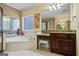 Sunlit bathroom featuring a jacuzzi tub with custom windows, vanity, and ceramic flooring at 3403 Bill Gardner Pkwy, Locust Grove, GA 30248