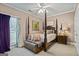 Cozy bedroom featuring a four-poster bed, soft lighting, and a beautiful butterfly art piece at 3403 Bill Gardner Pkwy, Locust Grove, GA 30248
