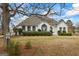 White brick house showing front yard with a large tree in the foreground and street address sign at 3403 Bill Gardner Pkwy, Locust Grove, GA 30248