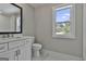 Bathroom with a white vanity, toilet, and a window overlooking the backyard at 110 Warren Way, Fayetteville, GA 30215