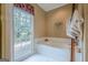 Inviting bathroom featuring a large soaking tub with a window view at 6360 Brookline Ct, Cumming, GA 30040