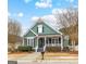 Inviting green home with a quaint front porch, lush landscaping, and curb appeal at 155 Stayman Park, Fayetteville, GA 30215