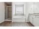 Bright bathroom featuring a soaking tub, walk-in shower, and stylish vanity with granite countertops at 604 Clark Lake Estates Dr, Grayson, GA 30017