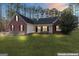 Charming brick and siding home with a well-manicured front lawn and inviting front porch, lit by landscape lighting at 1012 Matthews Way, Mcdonough, GA 30252