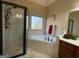 Elegant bathroom with separate glass shower and soaking tub with neutral tile and granite counters at 306 Oakwind Way, Canton, GA 30114