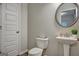 Cozy half bathroom featuring a toilet, pedestal sink, decorative mirror, and light gray walls for a clean and inviting space at 9068 Jim Purcell Dr, Covington, GA 30014