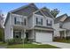 Charming two-story home with a gray exterior, stone accents, attached two car garage and a well manicured lawn at 9068 Jim Purcell Dr, Covington, GA 30014