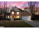 Charming two-story home with a stone facade, two-car garage, landscaped yard, and covered front porch at sunset at 190 Bridgemill Dr, Hampton, GA 30228