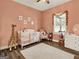 A stylish pink Bedroom featuring wood-look tile floors and a bright window with floral accents at 340 Cedar St, Social Circle, GA 30025