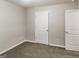Bedroom with carpeted floor, neutral walls, two white doors, and two electrical outlets at 323 Lauren Dr, Fairburn, GA 30213