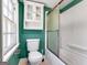 Cozy bathroom with green walls, a bathtub with glass doors, and a toilet at 927 Dean Patrick Rd, Locust Grove, GA 30248