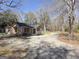 Home exterior with gravel driveway, surrounded by mature trees and a fenced yard at 927 Dean Patrick Rd, Locust Grove, GA 30248