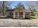 Charming bungalow style home with a covered front porch and gravel driveway, situated on a sunny day at 927 Dean Patrick Rd, Locust Grove, GA 30248