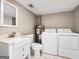 Functional laundry room with washer, dryer, water heater, utility sink, and a large mirror at 927 Dean Patrick Rd, Locust Grove, GA 30248