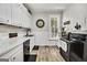 Traditional-style kitchen featuring white cabinets, black appliances, and a wood-look floor at 76 College St, Mcdonough, GA 30253