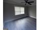 An empty bedroom featuring hardwood floors, neutral paint, a ceiling fan, and a window at 215 Buck Run, Loganville, GA 30052