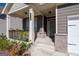 View of the covered front porch with decorative columns and custom wooden railing and brick supports at 7754 Hansel Ln, Lithonia, GA 30058