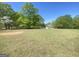 Acreage featuring rolling green grass, mature trees, and distant structures at 848 Still Rd, Lawrenceville, GA 30045