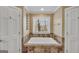 Bathroom featuring a white soaking tub with tile surround and natural light at 3075 Wood Valley Dr, Mcdonough, GA 30253