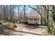 Back view of the house nestled among tall trees, featuring a back deck and sloping yard at 6255 James Rd, Austell, GA 30168