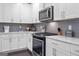 Well-equipped kitchen with stainless steel appliances, grey backsplash, white cabinets and marble countertops at 1968 Perry Nw Blvd, Atlanta, GA 30318