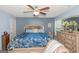 Bright bedroom features a patterned blue comforter, neutral walls, and a ceiling fan at 275 Bramble Bush Trl, Covington, GA 30014