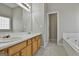 Bright bathroom with double sink vanity, tiled floor, and separate tub and doorway at 12241 Crestwood Ct, Fayetteville, GA 30215