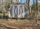 Outbuilding featuring weathered plank siding and white barn doors with a decorative cross, adding rustic charm at 114 Mcbride Rd, Fayetteville, GA 30215