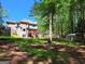 Lush backyard featuring a wooden deck, trampoline, storage shed, and mature trees at 65 Ashland Grove Ct, Sharpsburg, GA 30277