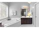 Bathroom with large soaking tub with white tile surround, vanity, large window, and a light fixture at 65 Ashland Grove Ct, Sharpsburg, GA 30277
