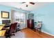 Light blue bedroom with hardwood floors, ceiling fan, desk with computer, and light brown curtains at 65 Ashland Grove Ct, Sharpsburg, GA 30277