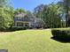Beautiful two-story home with stone accents, a covered porch, and a lush green lawn surrounded by mature trees at 65 Ashland Grove Ct, Sharpsburg, GA 30277