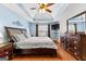 A luxurious main bedroom with tray ceilings, a ceiling fan, and a large bed at 65 Ashland Grove Ct, Sharpsburg, GA 30277