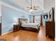 A main bedroom with tray ceilings, wooden floors, a ceiling fan, and a large bed at 65 Ashland Grove Ct, Sharpsburg, GA 30277