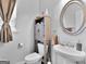 Cozy bathroom with a white toilet, a sink, a round mirror, and a wooden cabinet at 340 Layfield Dr, Jonesboro, GA 30238