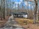 Single story home with long driveway, surrounded by forest and autumn leaves at 1436 Heritage Ct, Villa Rica, GA 30180