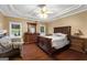 Primary bedroom featuring a tray ceiling, hardwood floors, with a dresser and a backyard view at 605 Clearwater Ct, Mcdonough, GA 30252