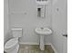 Clean half bath with pedestal sink, toilet, mirror, and towel rack at 483 Fairlane Nw Cir, Atlanta, GA 30331