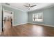 This bedroom features wood floors, modern ceiling fan and neutral light blue walls and view to kitchen at 1185 Old Greenville Rd, Fayetteville, GA 30215