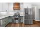 Modern kitchen showcasing stainless steel appliances, white cabinets, and a decorative wooden range hood at 1185 Old Greenville Rd, Fayetteville, GA 30215