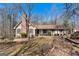 Inviting ranch-style home featuring a brick chimney, complemented by bare trees in a natural setting at 135 Flat Creek Ct, Fayetteville, GA 30214