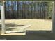 An outdoor living space on a back porch with view of the grass covered backyard with a tree line at 85 Crabapple Ridge Dr, Oxford, GA 30054