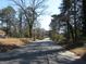 A view of the neighborhood street and the side of a house nestled among mature trees at 1876 Sw Sandtown Sw Rd, Atlanta, GA 30311