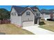 A view of the house and driveway featuring an attached two-car garage and manicured lawn at 7019 Diamond Dr, Rex, GA 30273